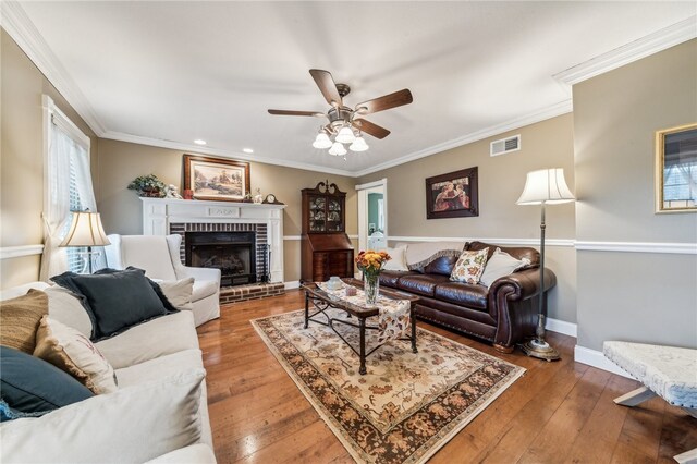 living room featuring a fireplace, wood-type flooring, ceiling fan, and crown molding