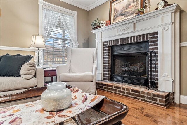 living room featuring a brick fireplace, wood-type flooring, and crown molding