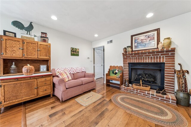 living room with a brick fireplace and light hardwood / wood-style flooring