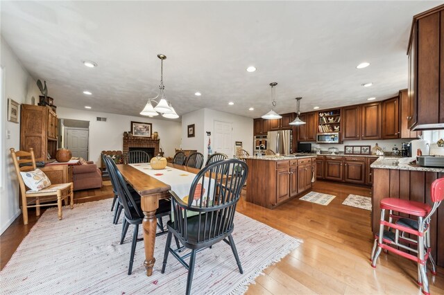 dining space featuring a fireplace and light hardwood / wood-style flooring