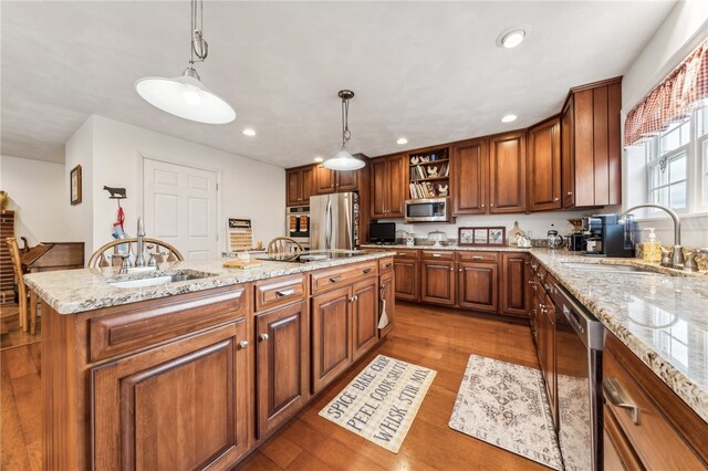 kitchen featuring a kitchen island, appliances with stainless steel finishes, decorative light fixtures, sink, and light hardwood / wood-style floors