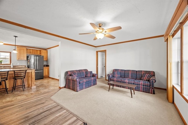 living room with ceiling fan, a textured ceiling, light wood-type flooring, and crown molding