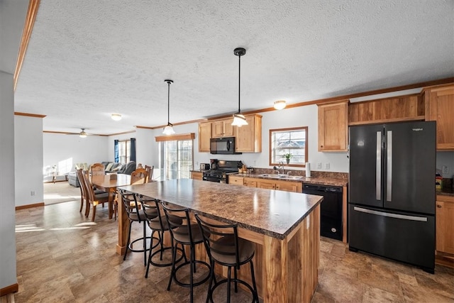 kitchen featuring pendant lighting, a textured ceiling, black appliances, and sink