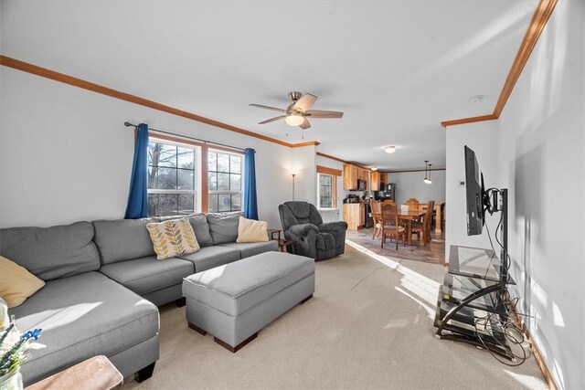 living room featuring ceiling fan, crown molding, and light colored carpet