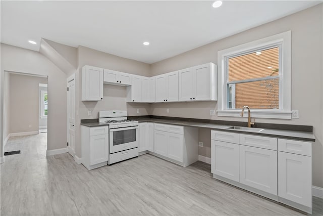 kitchen featuring gas range gas stove, white cabinetry, a wealth of natural light, and sink