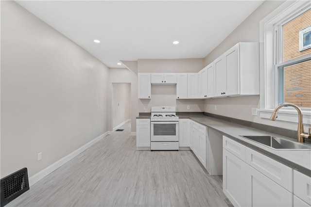 kitchen with light wood-type flooring, white cabinetry, sink, and white stove