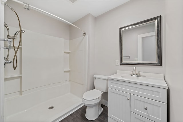 bathroom with toilet, a shower, vanity, and wood-type flooring