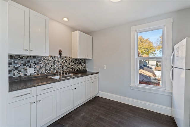 kitchen with white cabinets, sink, dark hardwood / wood-style floors, white fridge, and backsplash