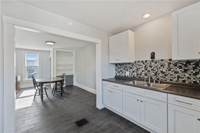 kitchen featuring white cabinets, decorative backsplash, dark wood-type flooring, and sink