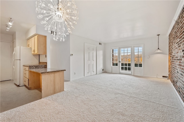 kitchen with white fridge, decorative light fixtures, light brown cabinets, light colored carpet, and brick wall