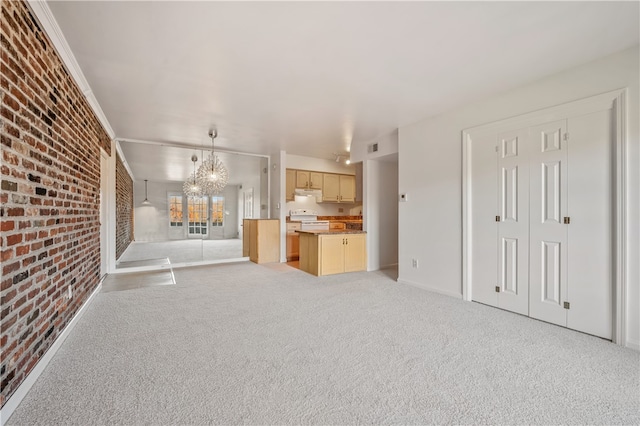 unfurnished living room with brick wall, light carpet, and an inviting chandelier