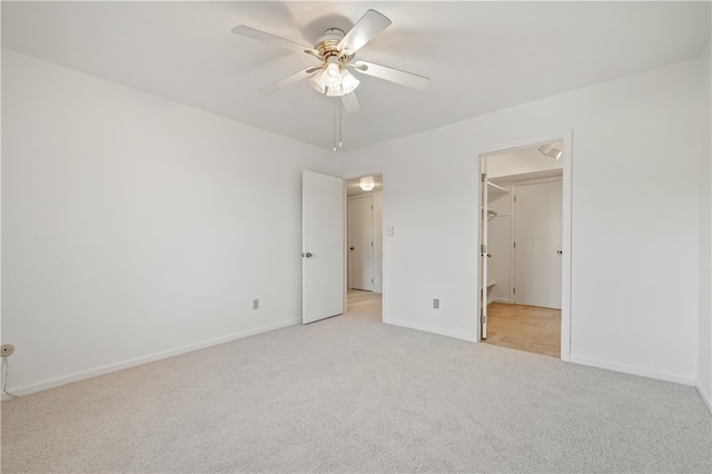 unfurnished bedroom with ceiling fan, light carpet, a closet, and a walk in closet