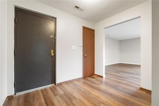 foyer with a textured ceiling and light hardwood / wood-style flooring