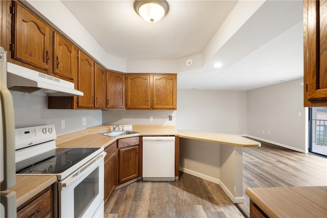 kitchen featuring light hardwood / wood-style floors, sink, a breakfast bar, kitchen peninsula, and white appliances