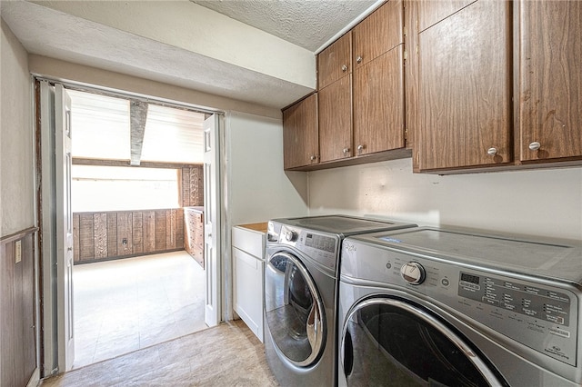 washroom featuring cabinets, washer and dryer, and a textured ceiling