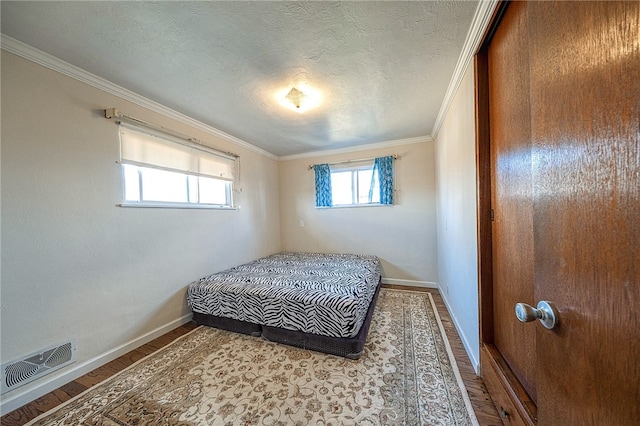 bedroom with a textured ceiling, hardwood / wood-style flooring, and crown molding