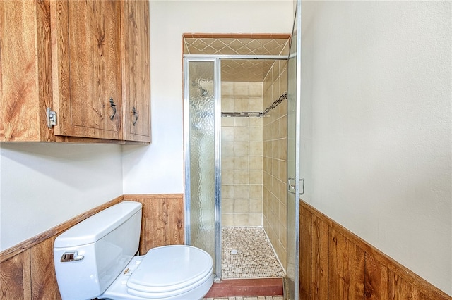 bathroom featuring a shower with shower door, wooden walls, and toilet