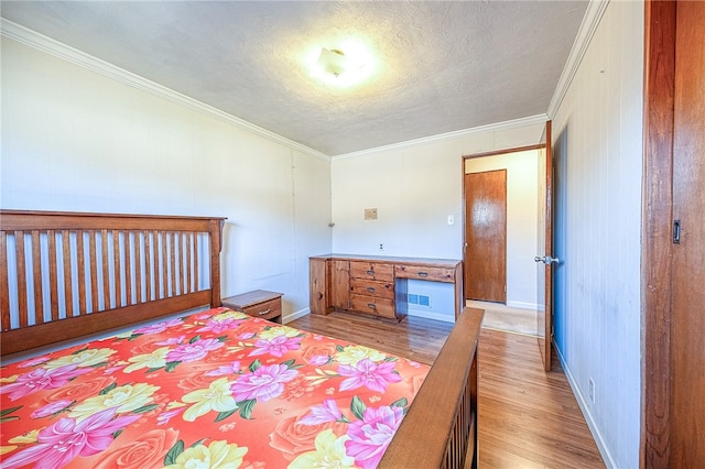 bedroom with light hardwood / wood-style flooring, built in desk, and crown molding