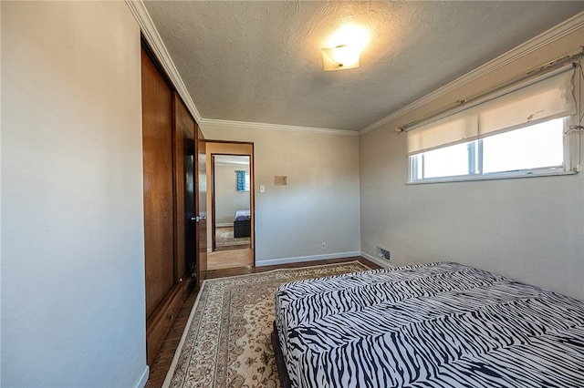 bedroom with hardwood / wood-style floors, a textured ceiling, a closet, and ornamental molding