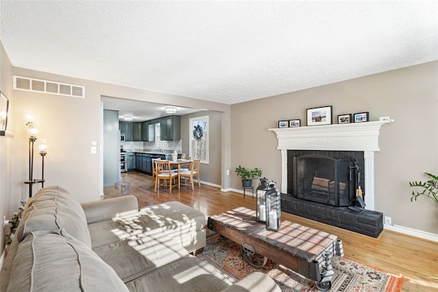 living room with a fireplace, a textured ceiling, and hardwood / wood-style flooring