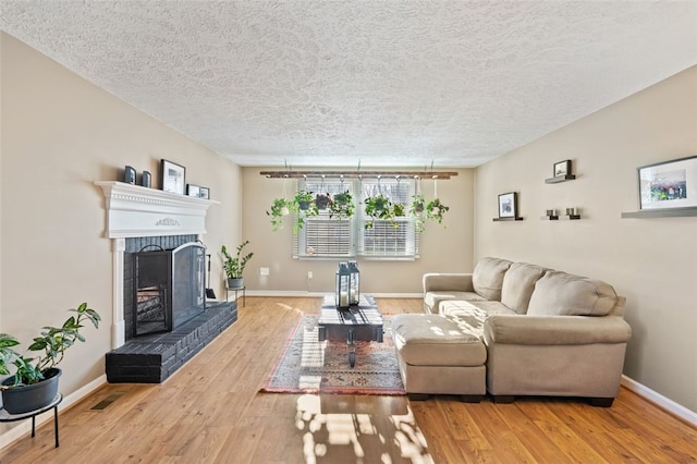 living room with hardwood / wood-style flooring, a fireplace, and a textured ceiling