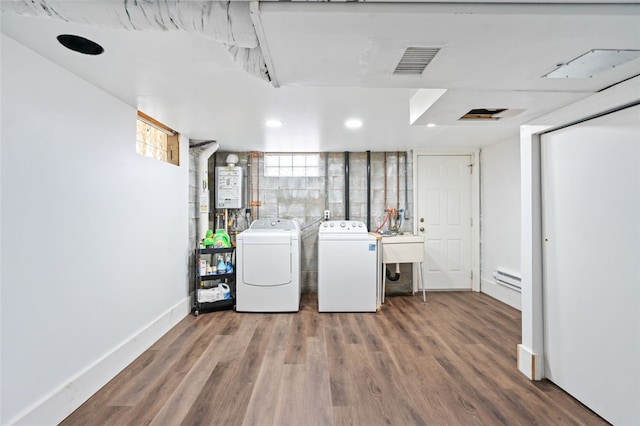 laundry room featuring washer and clothes dryer, plenty of natural light, dark wood-type flooring, and a baseboard radiator