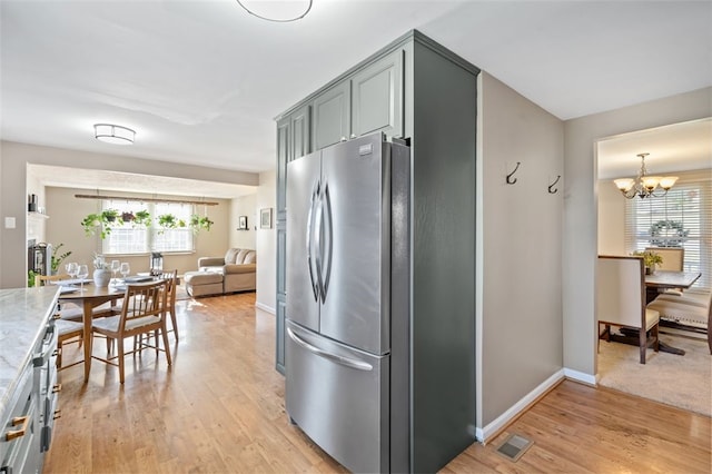 kitchen featuring a notable chandelier, stainless steel fridge, a healthy amount of sunlight, and light hardwood / wood-style flooring