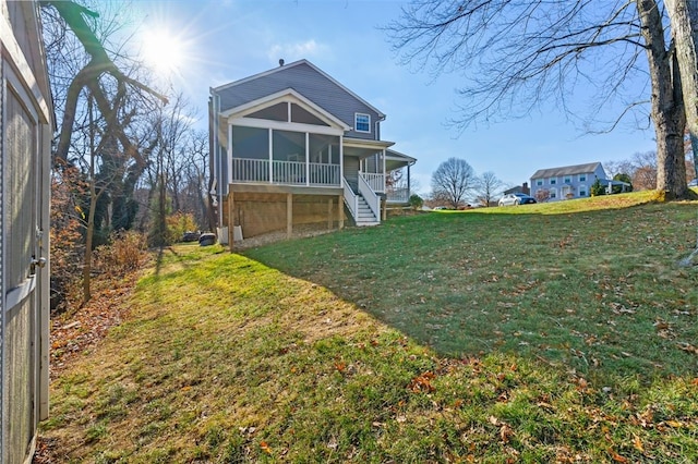 rear view of property featuring a yard and a sunroom