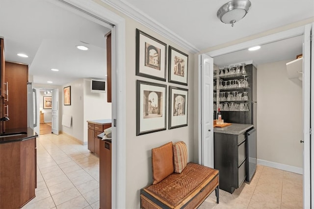 hallway with sink, crown molding, and light tile patterned floors