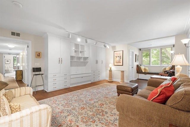 living room with dark wood-type flooring and track lighting