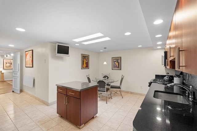 kitchen with light tile patterned floors, range, sink, and a kitchen island