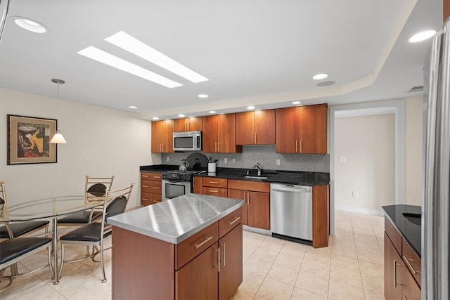 kitchen featuring a center island, sink, backsplash, appliances with stainless steel finishes, and decorative light fixtures