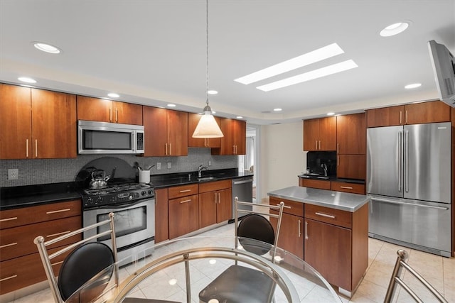 kitchen featuring tasteful backsplash, appliances with stainless steel finishes, pendant lighting, sink, and a skylight