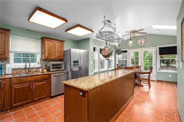 kitchen with tasteful backsplash, vaulted ceiling with skylight, a wealth of natural light, and stainless steel appliances