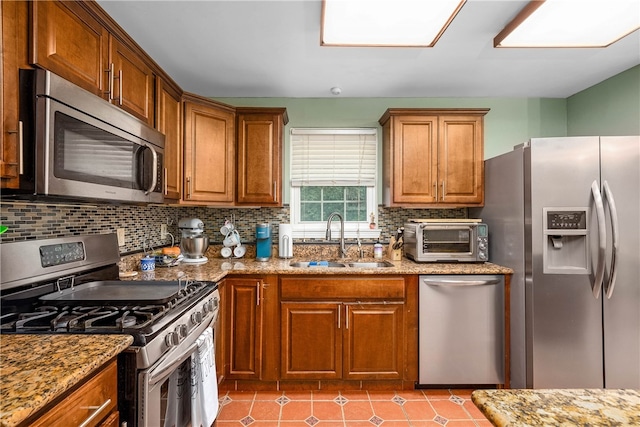 kitchen featuring backsplash, appliances with stainless steel finishes, sink, and light stone counters