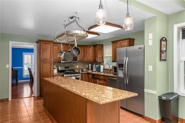 kitchen featuring a kitchen island, appliances with stainless steel finishes, pendant lighting, decorative backsplash, and sink