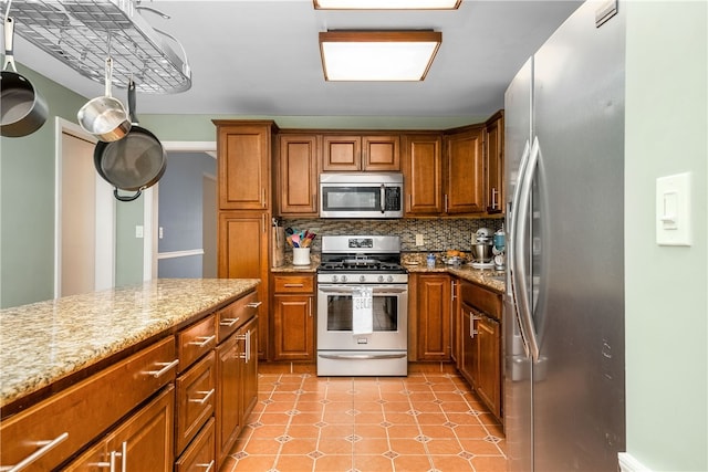 kitchen with stainless steel appliances, tasteful backsplash, and light stone countertops