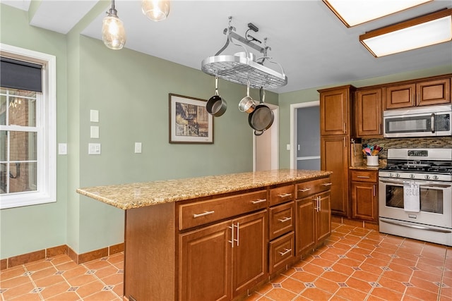 kitchen featuring light stone counters, appliances with stainless steel finishes, backsplash, decorative light fixtures, and a center island