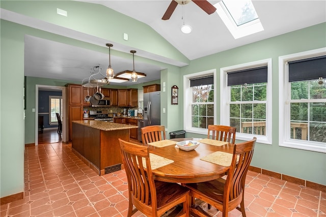 tiled dining room with ceiling fan and lofted ceiling with skylight