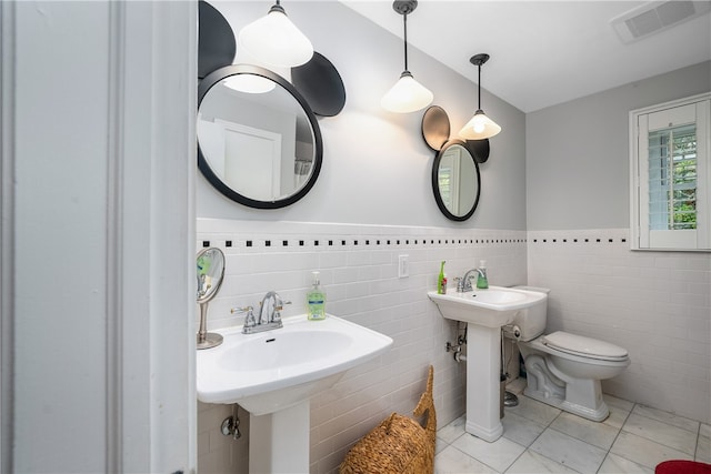 bathroom featuring toilet, tile walls, and tile patterned flooring