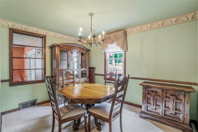 dining room with light colored carpet and a chandelier