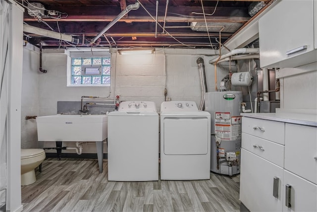 laundry room with washing machine and dryer, sink, gas water heater, and light hardwood / wood-style floors