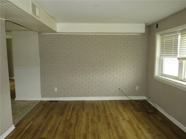 spare room with brick wall and dark hardwood / wood-style floors