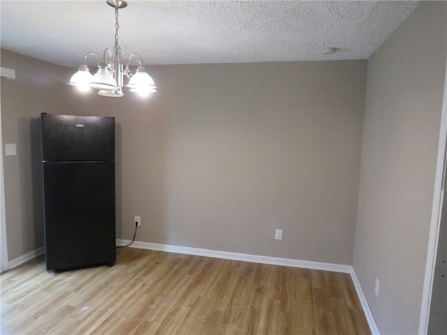 interior space featuring light hardwood / wood-style floors, a notable chandelier, and a textured ceiling