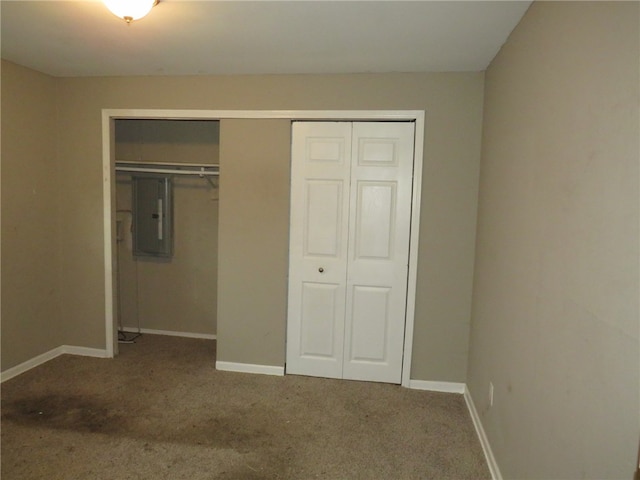 unfurnished bedroom with electric panel, carpet floors, and a closet