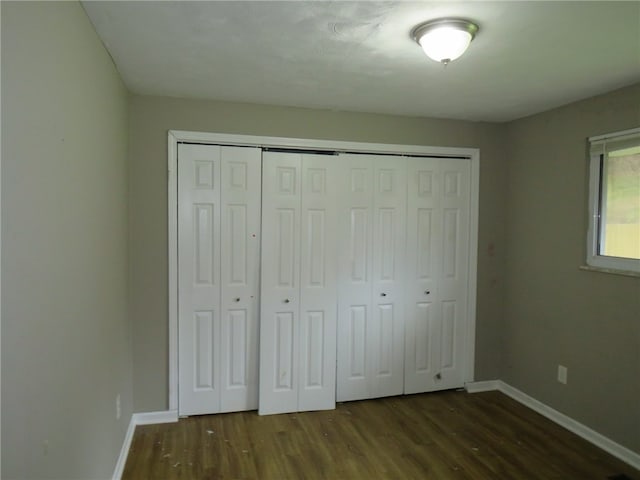 unfurnished bedroom featuring dark hardwood / wood-style flooring and a closet