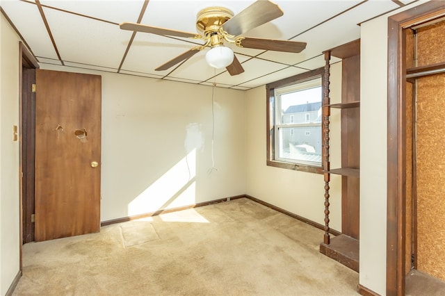 unfurnished room with a paneled ceiling, ceiling fan, and light carpet