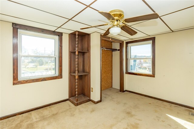 unfurnished bedroom with a paneled ceiling, ceiling fan, and multiple windows