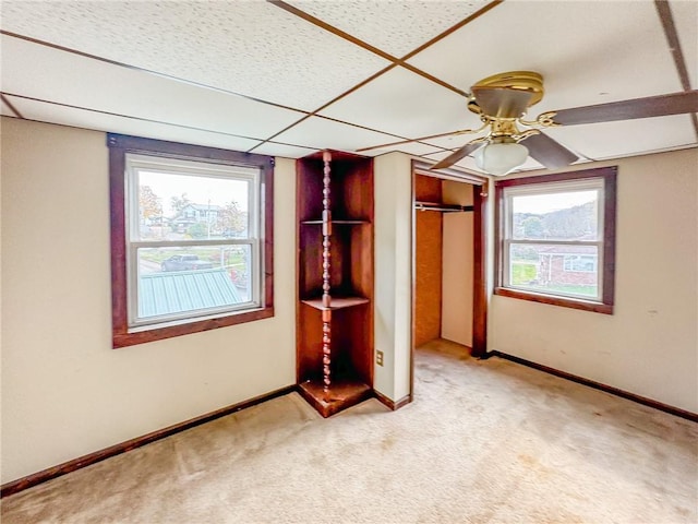 unfurnished bedroom featuring a closet, ceiling fan, a drop ceiling, and light colored carpet