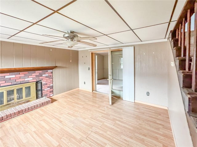 unfurnished living room with ceiling fan, a drop ceiling, light hardwood / wood-style floors, and a brick fireplace